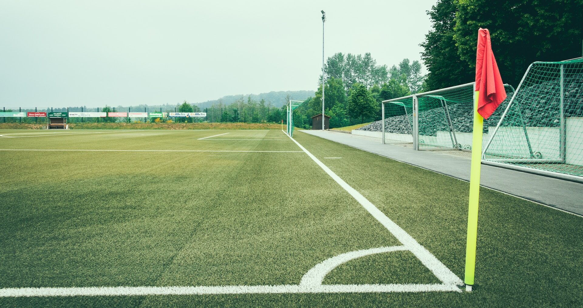 Red corner flag and football pitch.